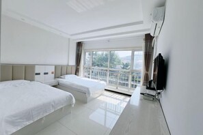 A hotel room with two beds, a TV, and a balcony with a view.