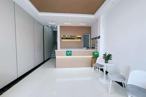 A reception area with a reception desk, a staircase, and a seating area with a small table and chairs. - Home Inn Huayi Hotel (Changdao Scenic Area) (Yantai)