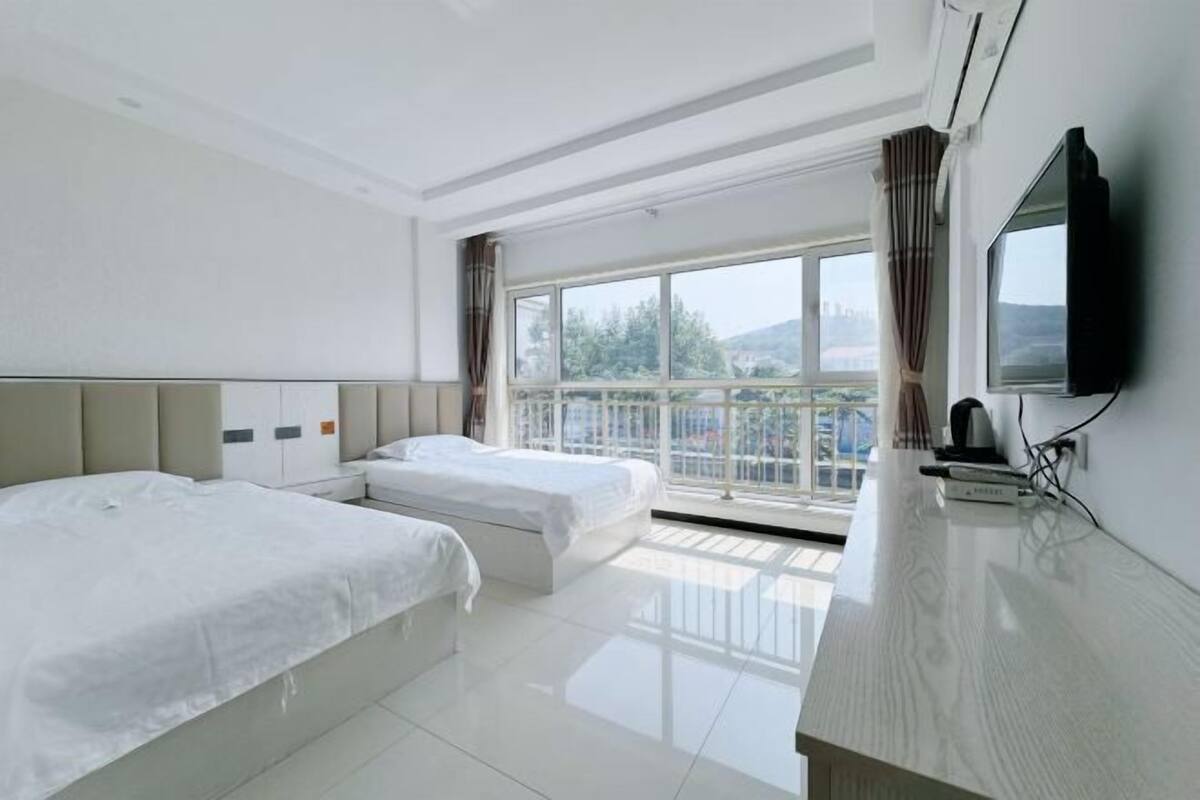 A hotel room with two beds, a TV, a balcony with a view, and a modern design.