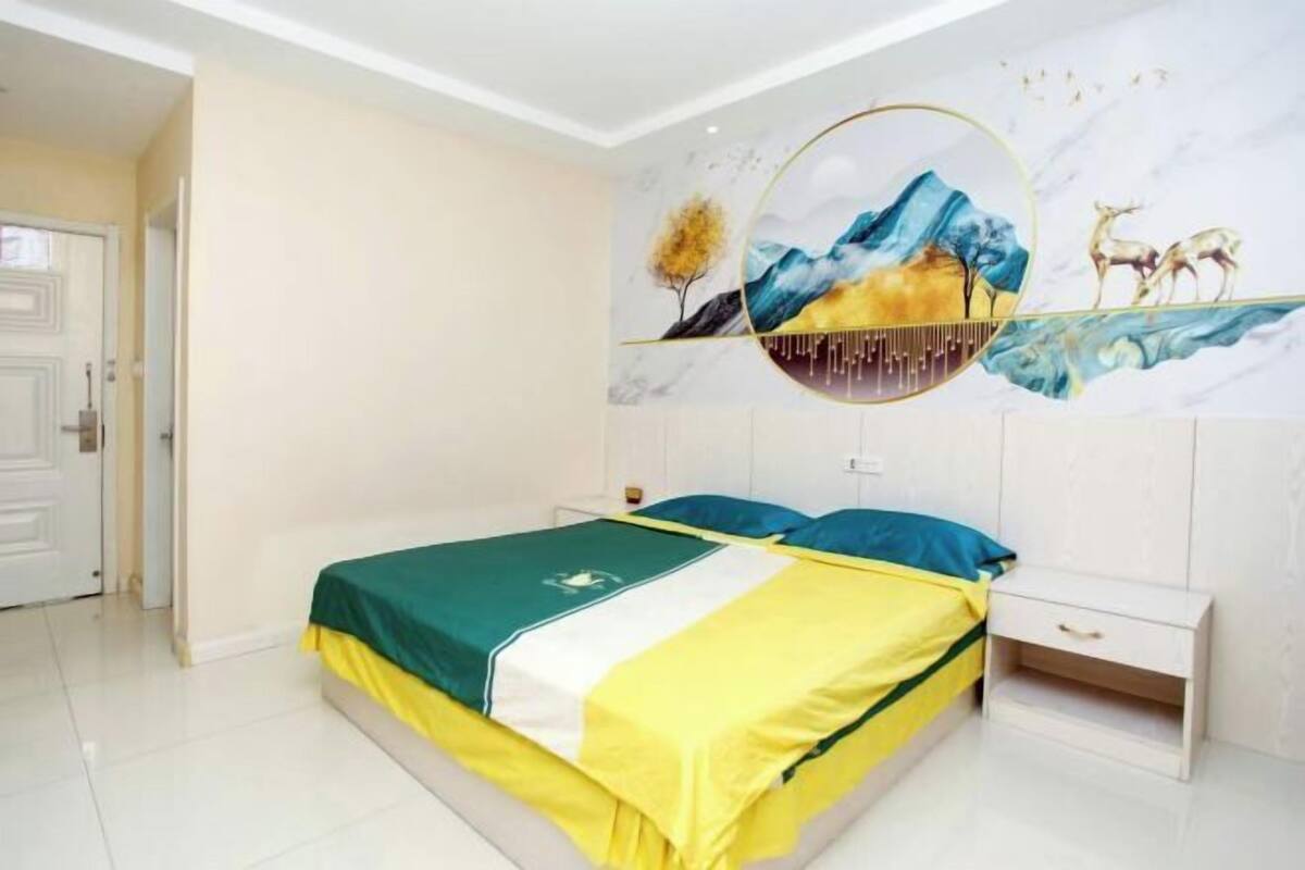 A bedroom with a bed, nightstand, and a wall mural.