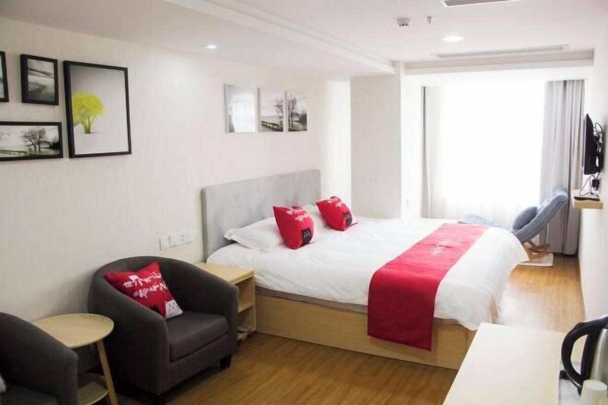 A hotel room with a bed, a desk, a chair, and artwork on the walls.
