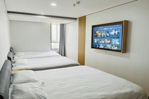A hotel room with two beds, a large digital screen displaying various images, and a window with curtains. - AAliansuojiudian (Shanghai)
