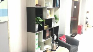 A living room with a sofa, a small table with a kettle, and a bookshelf with various items. - AAliansuojiudian (Shanghai)