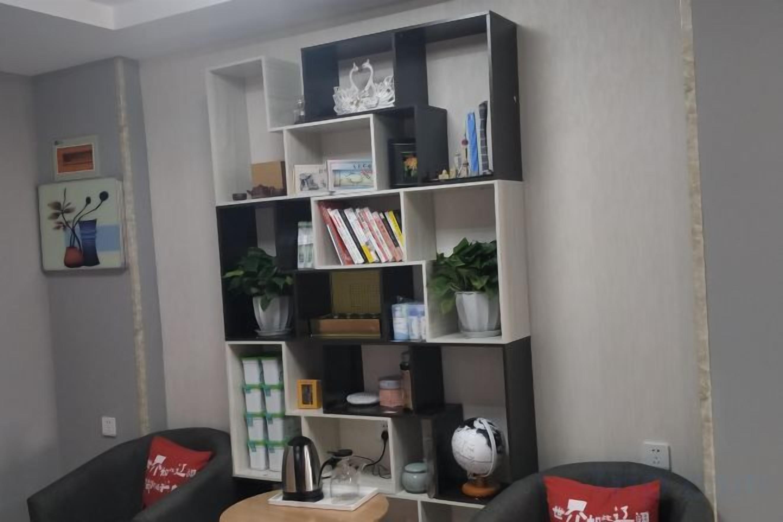 A living room with a bookshelf, two chairs, and a coffee table.