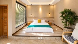 Une chambre à coucher moderne avec un lit, des tables de chevet, une plante en pot et une vue sur l’extérieur.