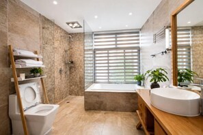 Een moderne badkamer met een badkuip, toilet, wastafel en douche.