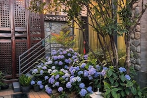 A wooden staircase with a metal railing leading to a stone wall. - Serene Mystery Garden (Dali City)