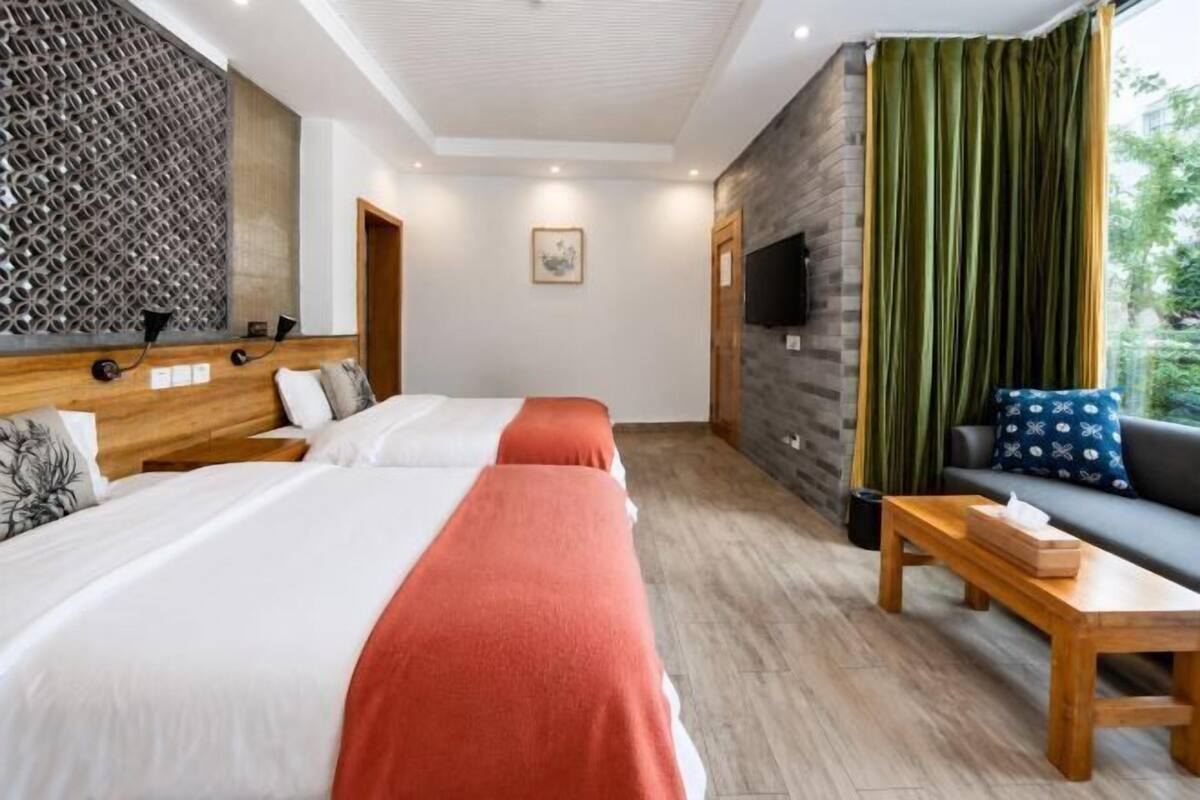 Een hotelkamer met twee bedden, een bank, een televisie en een houten tafel.