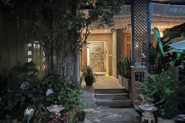 A pathway leading to a building entrance with steps and potted plants.