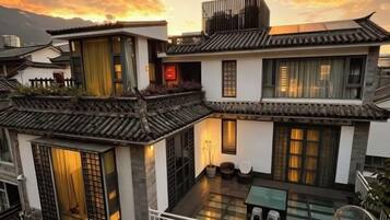 Un edificio tradicional de varios pisos con un balcón, ventanas amplias y un patio.