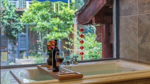 Une salle de bain avec une baignoire, une fenêtre et une vue sur la verdure.