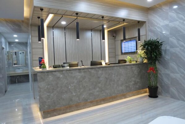 A reception area with a marble counter, pendant lighting, a television, and a potted plant. - Thank You Inn (Shanghai Xianghuaqiao) (Shanghai)