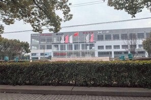 A modern building with a glass facade, multiple windows, and a flat roof. - Thank You Inn (Shanghai Xianghuaqiao) (Shanghai)