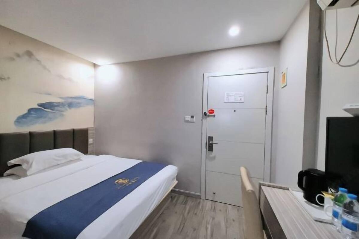 A hotel room with a bed, a desk, and a door.