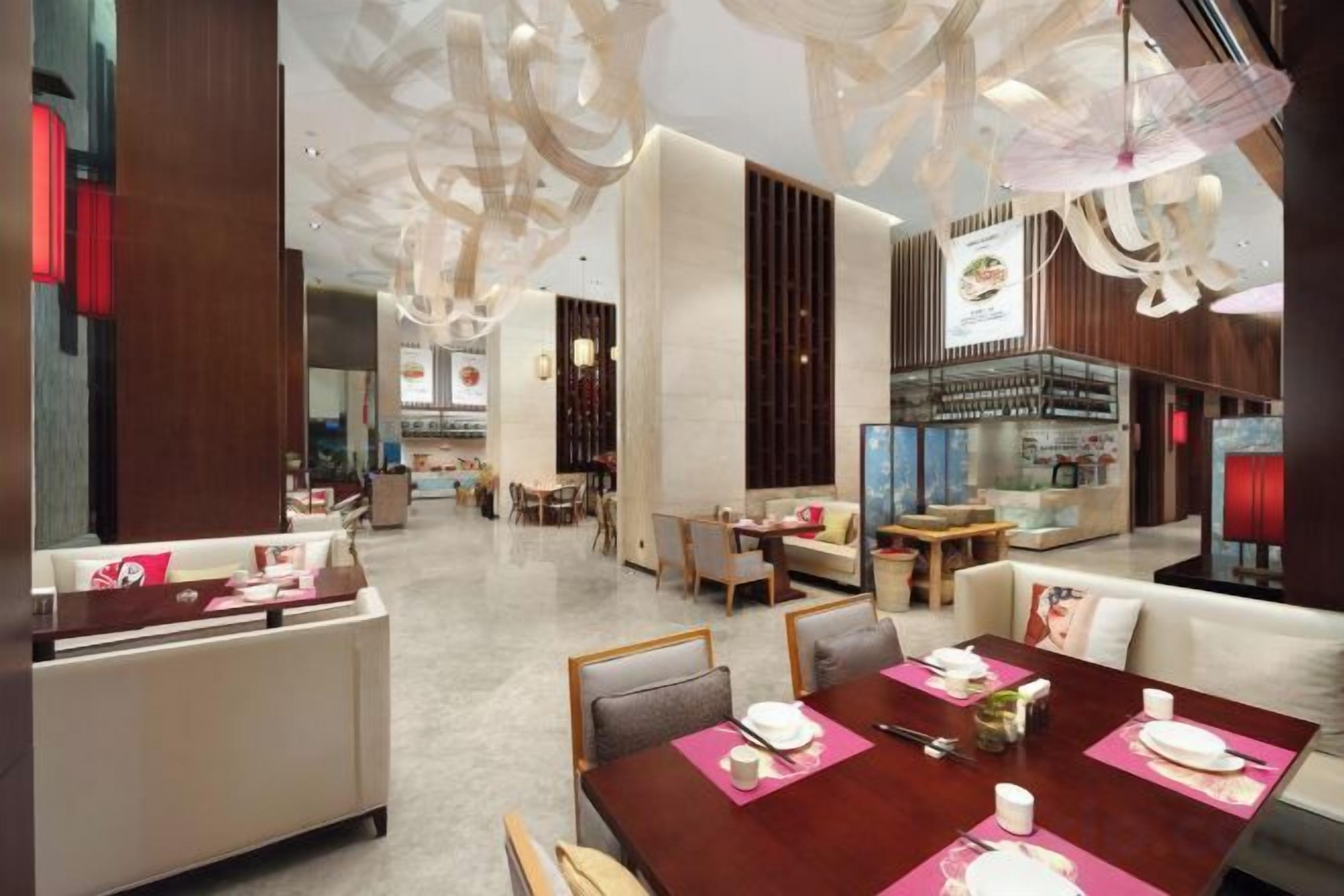 A modern hotel lobby with a dining area, seating arrangements, and a bar.