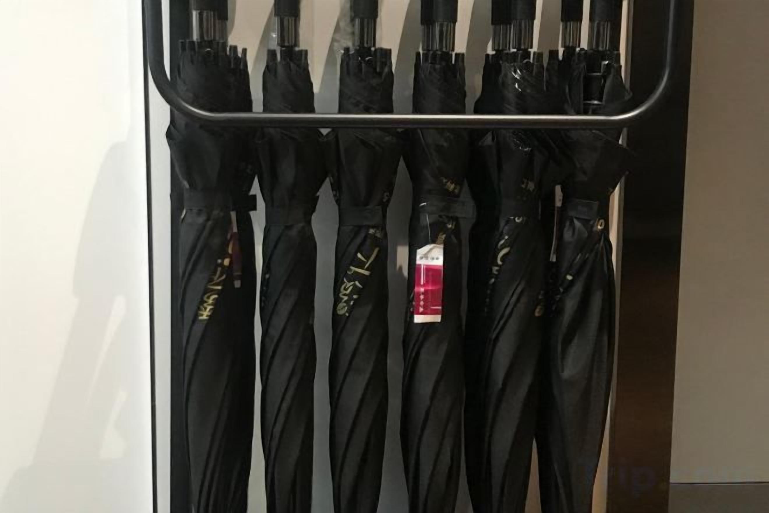 Várias ombrelas pretas penduradas em um suporte.