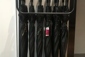 Una fila de sombrillas negras colgadas en un perchero.