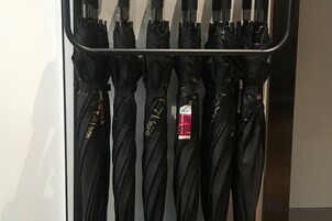 A row of black umbrellas hanging on a rack.