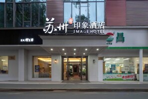 A hotel entrance with a sign that reads 'JIMAGE HOTEL' and a storefront with a green sign. - Suzhou Impression Hotel (Pingxiang)