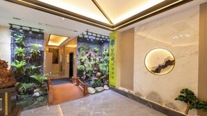 A lobby with a marble floor, a wooden staircase, and a wall with a circular decorative element. - Suzhou Impression Hotel (Pingxiang)