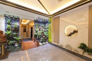 A hotel lobby with a wooden staircase, a reception desk, and a wall with a circular decorative element. - Suzhou Impression Hotel (Pingxiang)
