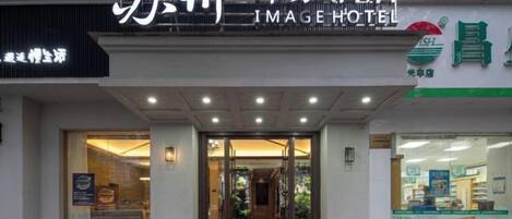 Entrada de un hotel con un cartel que dice 'Image Hotel' y un escaparate visible con una etiqueta de precio de 85.