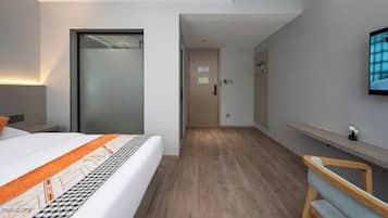 Een moderne hotelkamer met een bed, een bureau, een stoel en een televisie aan de muur.