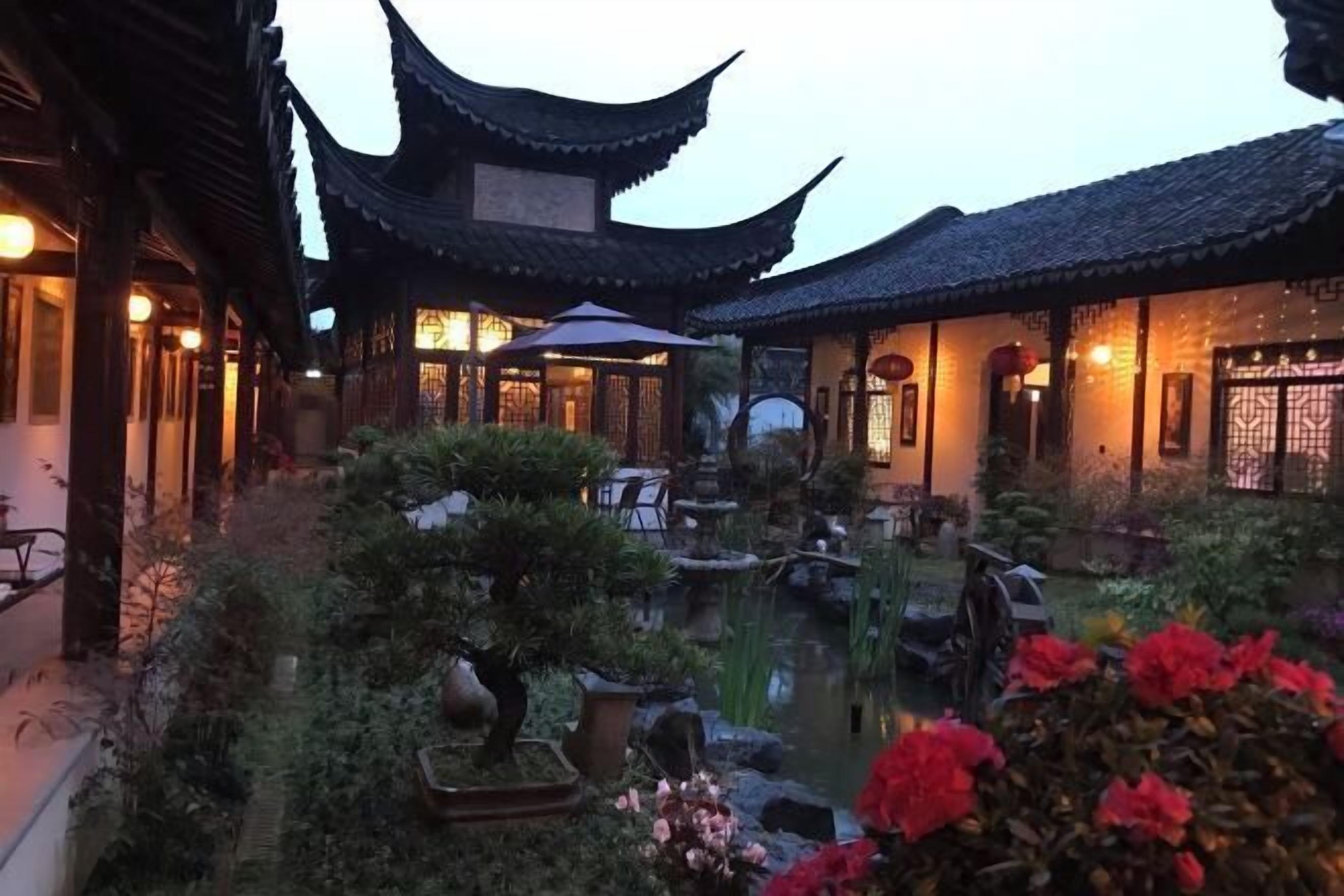 A traditional courtyard with a pond, potted plants, and a small bridge.