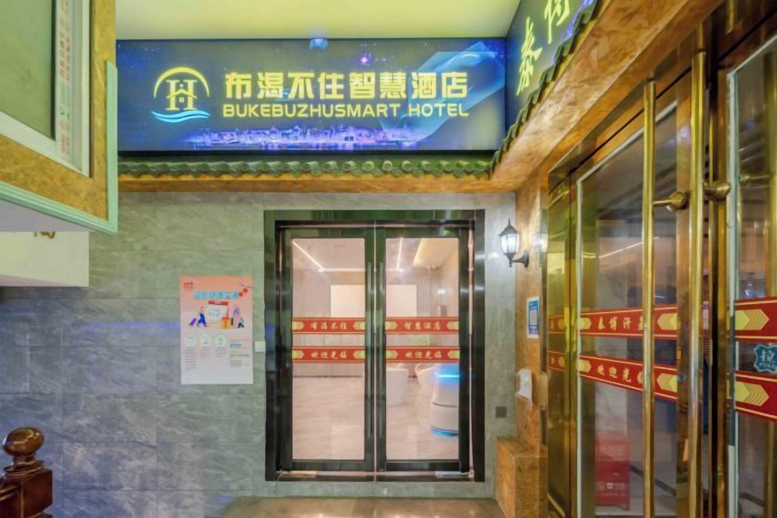 The entrance of BUKEBUZHUSMART HOTEL with a glass door and a sign above.