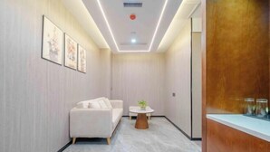 Una habitación moderna con un sofá, una pequeña mesa redonda y cuadros en la pared.