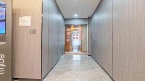Un pasillo moderno de hotel con paneles de madera y suelo de mármol.