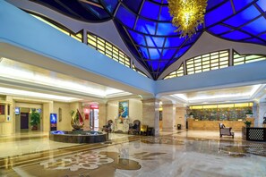 A spacious lobby with a high ceiling, a reception desk, seating areas, and a decorative fountain. - SOFIS PINGSHAN HOTEL (Fuzhou)