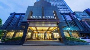 De ingang van Hotel Sofis met een modern ontwerp, met een glazen gevel en een opvallende entree met treden.