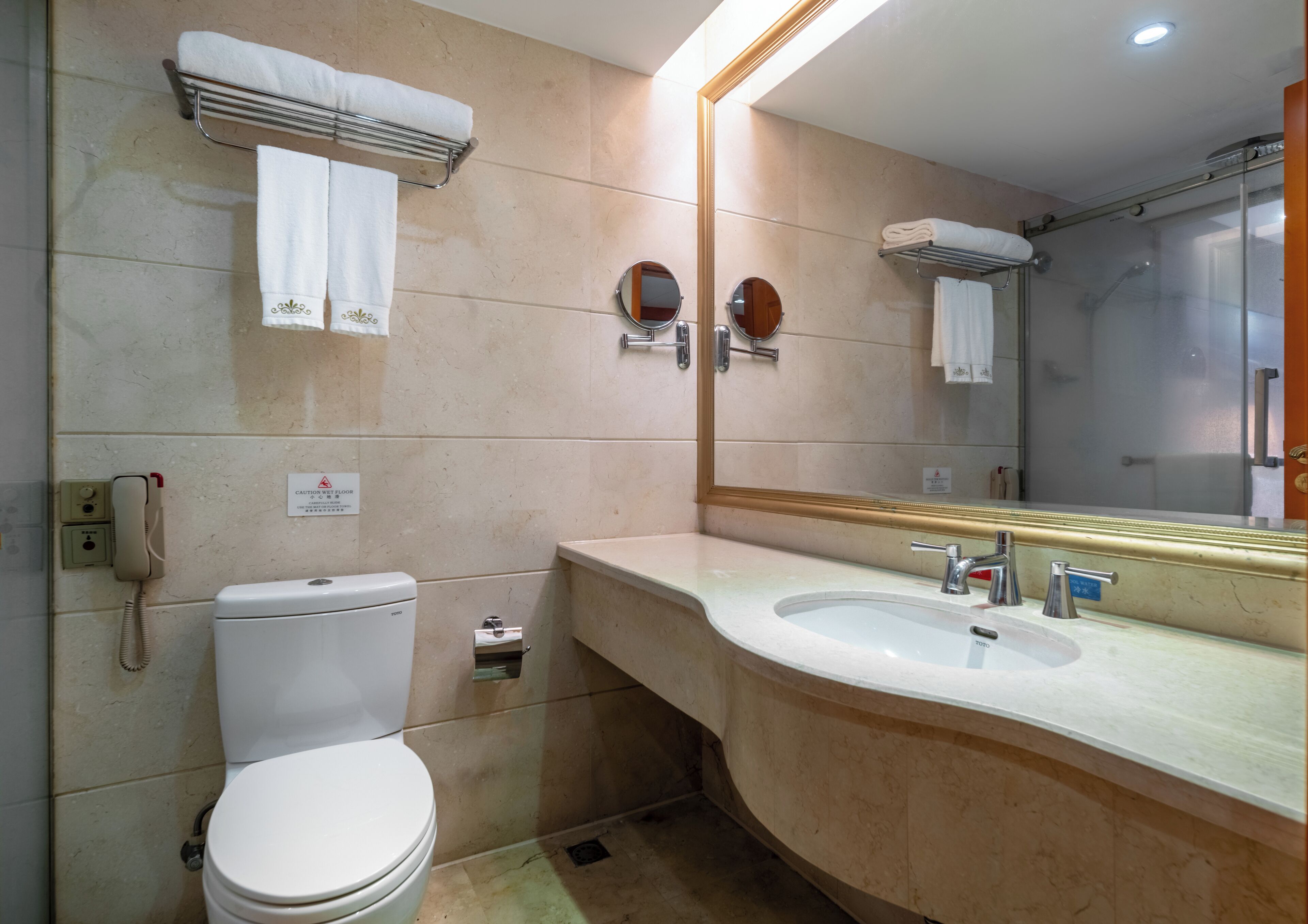Bagno con WC, lavabo e doccia. Sopra il lavabo c'è uno specchio e sopra il WC un porta asciugamani.