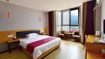 Habitación de hotel con cama, escritorio, silla y vistas al exterior.
