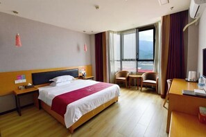 Ein Hotelzimmer mit Bett, Schreibtisch, Stuhl und Blick ins Freie.