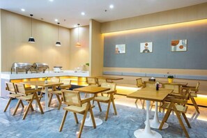 Un espace repas moderne avec des tables et des chaises, un comptoir avec une machine à café et des œuvres d’art murales.
