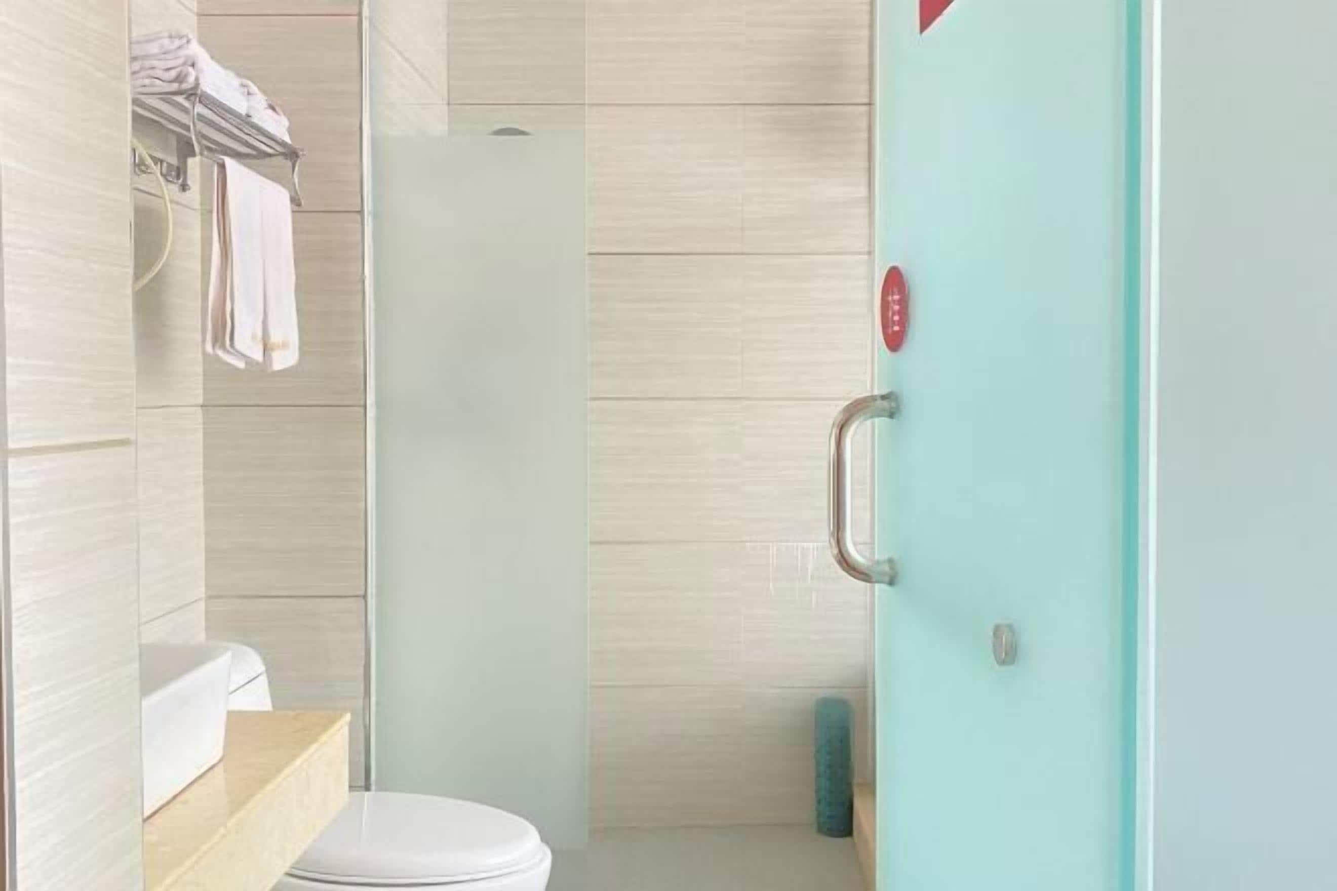 A modern bathroom with a toilet, a glass shower enclosure, and a towel rack.