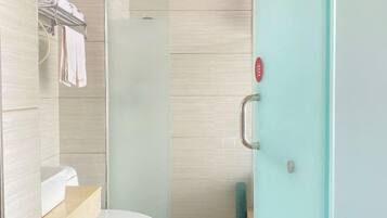 A modern bathroom with a toilet, a glass shower enclosure, and a towel rack.
