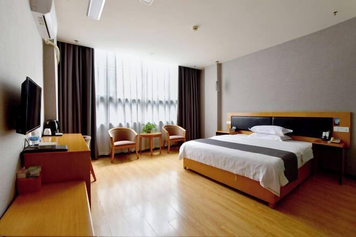Habitació d'hotel amb un llit, un escriptori, una cadira, una taula petita i un televisor.