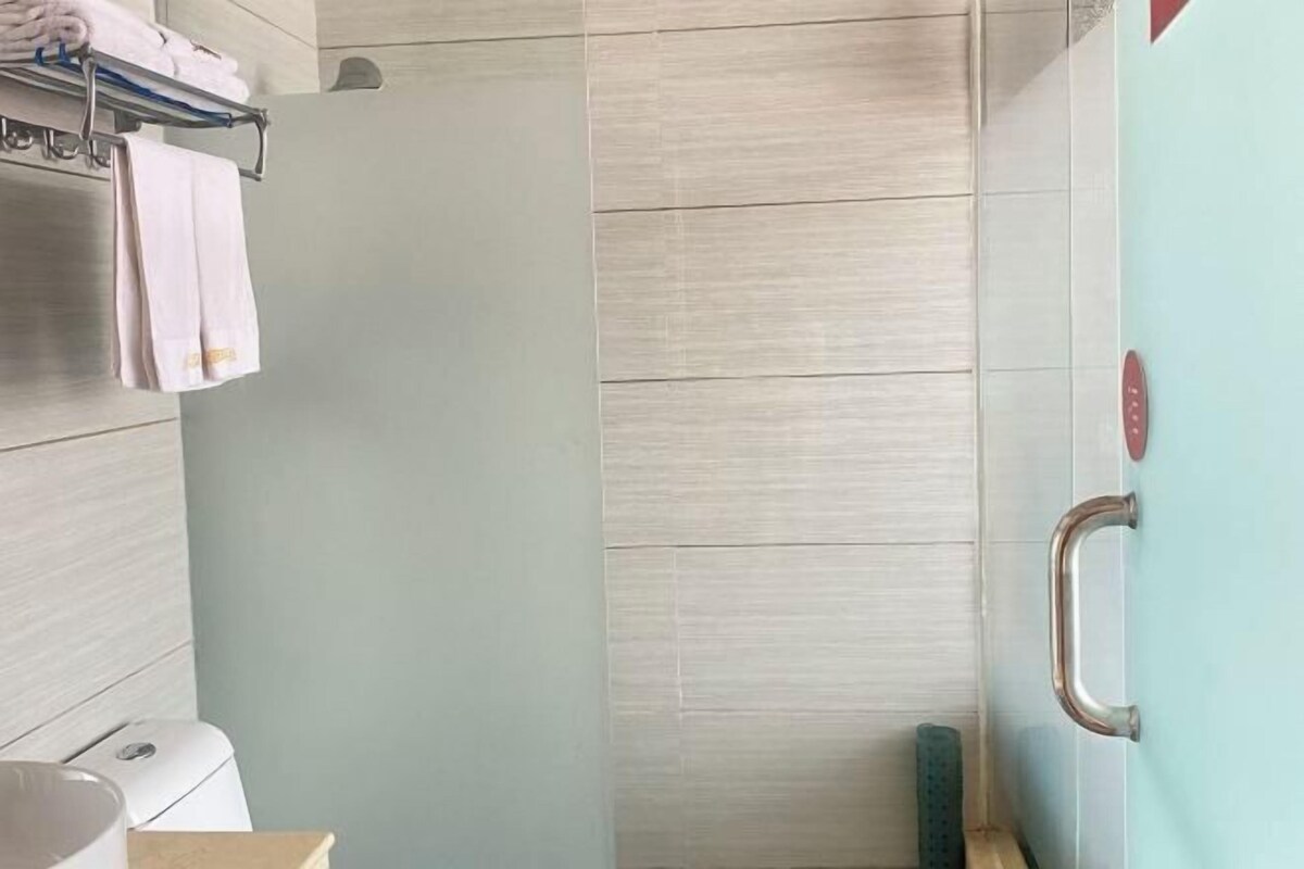 Ein Badezimmer mit Dusche, Handtuchhalter und Toilette.