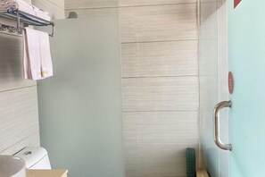Ein Badezimmer mit Dusche, Handtuchhalter und Toilette.