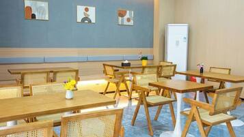 Un comedor con mesas y sillas de madera, un refrigerador blanco y decoración en la pared.