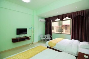 Une chambre d’hôtel avec deux lits, une télévision, un bureau et une fenêtre avec des rideaux.