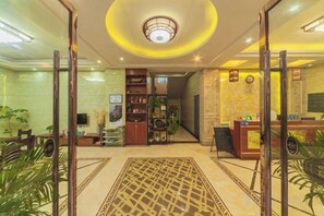 Un hall d’hôtel comprenant un comptoir d’accueil, un espace salon et un escalier menant aux étages supérieurs.