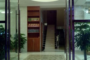 A lobby with a staircase, a wooden cabinet with bottles, and a potted plant. - Renhua Danzhilv Residence (Renhua)