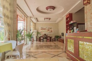 Un hall de hotel con mostrador de recepción, zona de estar y un cuadro abstracto grande en la pared.