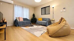 Un soggiorno moderno con un divano, un pouf, un tavolino da caffè, un piccolo tavolino e una lampada da terra.