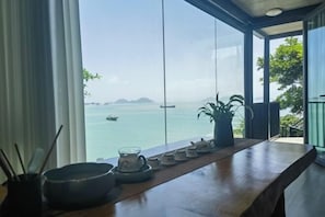 A view from a room with a large window overlooking a body of water and distant islands.