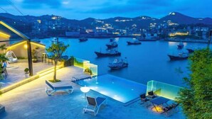 A rooftop terrace with lounge chairs and a glass balustrade overlooking a harbor with boats. - Between sky and sea (Wenling)